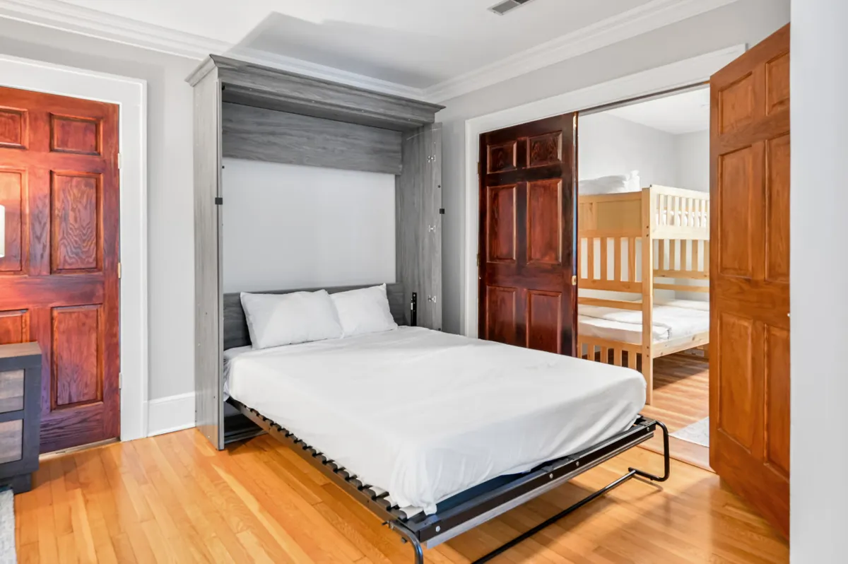 A cozy family bedroom with both a murphy bed and bunk beds, wood accents, and soft lighting. The layout creates a playful yet restful environment, perfect for children’s sleepovers or additional sleeping space for larger groups.