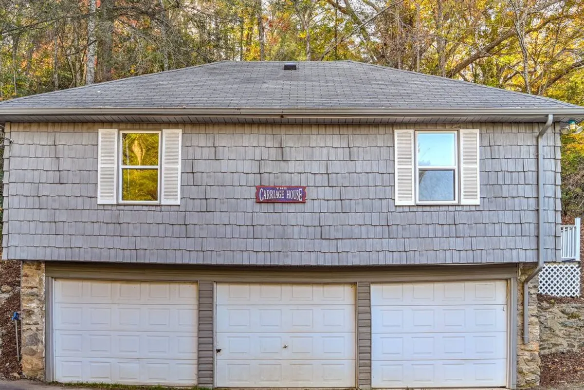 The exterior of the charming carriage house, distinguished by its 'Carriage House' sign, shingle siding, and double garage doors. The structure stands apart, offering a sense of privacy and retreat.